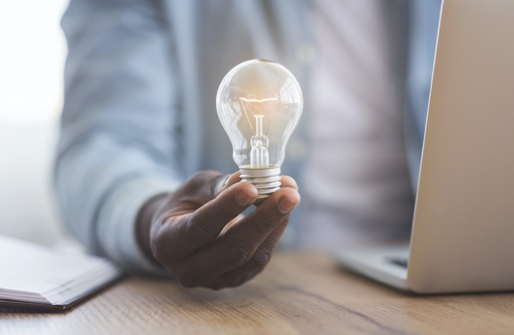 Black businessman holding illuminated light bulb in hand